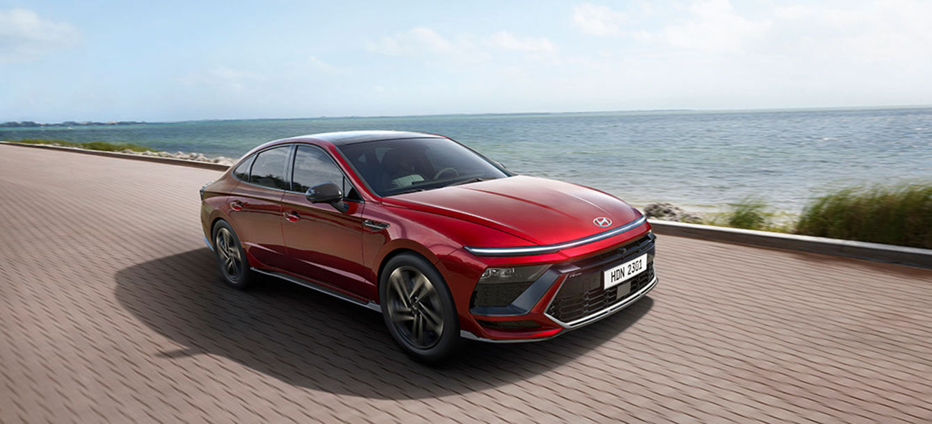 Side-front view of orange Grandi10 with lakeside view at night
